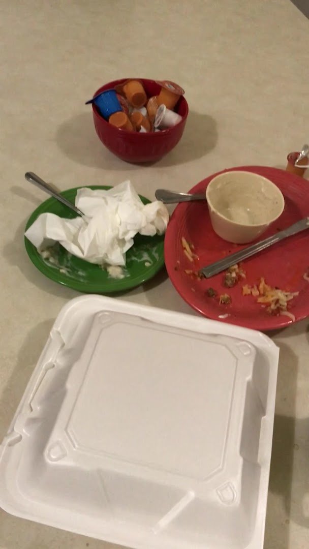 Breakfast plates on a table beside coffee cups.